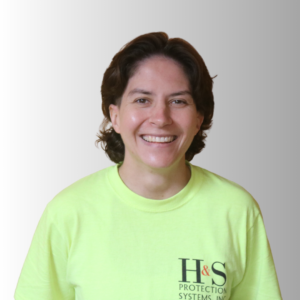 Smiling woman in a neon green t-shirt with H&S Protection Systems logo, portrait against a gray gradient background.